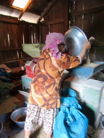 Dans sa petite fabrique sous sa maison, cette femme traite les grains de riz pour enlever leur enveloppe brune. Les grains proviennent des habitants des environs qui ont fait sécher leur production au soleil, sur une grande bâche, devant leur maison. Chhlong, Cambodge.